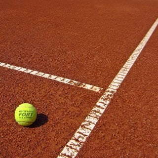 Campo de tenis rojo con pelota